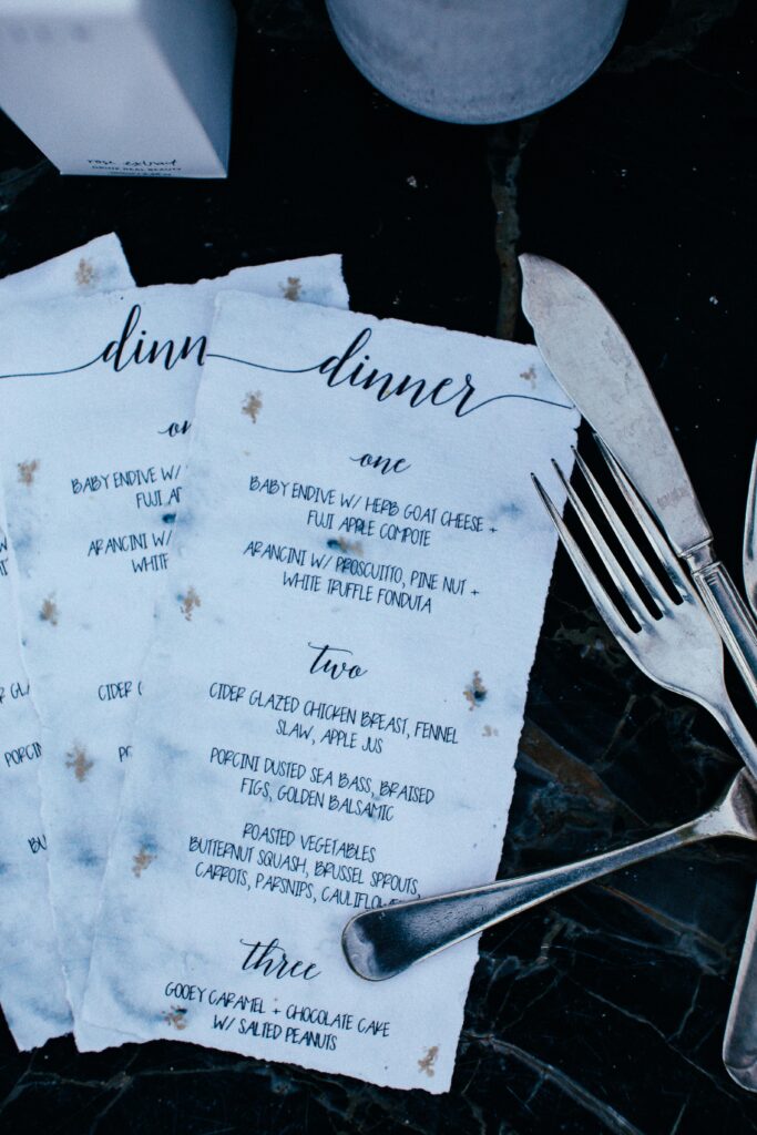 Close-up of a restaurant dinner menu with fork and knife, elegant dining setting.